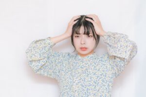 頭を抱えて落ち込む女性（遺品整理でうつ・無気力のイメージ）